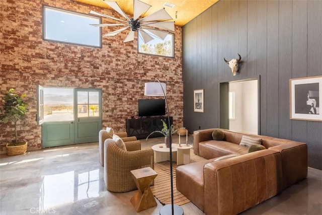 living room featuring a healthy amount of sunlight, high vaulted ceiling, ceiling fan, and wooden walls