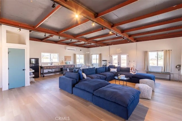 living room featuring a wealth of natural light, beamed ceiling, light hardwood / wood-style flooring, and a wall mounted air conditioner