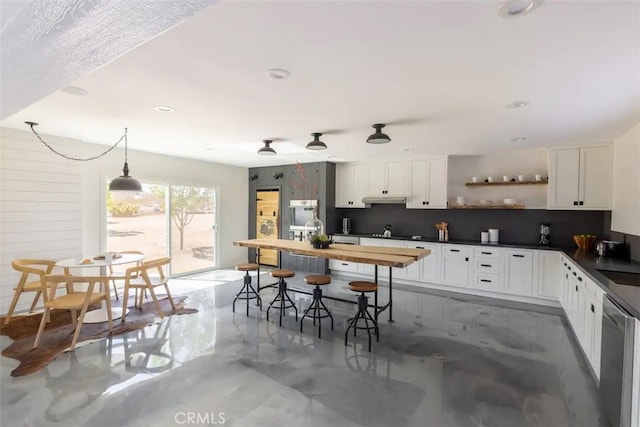 kitchen with decorative backsplash, hanging light fixtures, sink, stainless steel dishwasher, and white cabinetry