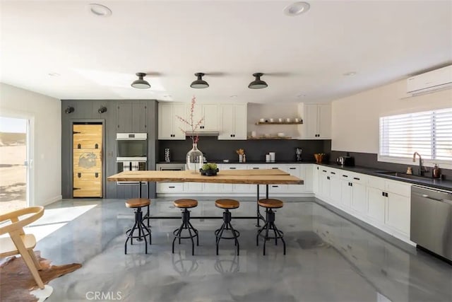 kitchen with white cabinetry, concrete floors, stainless steel appliances, and sink