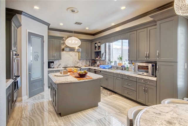 kitchen featuring hanging light fixtures, gray cabinets, stainless steel appliances, a center island, and crown molding