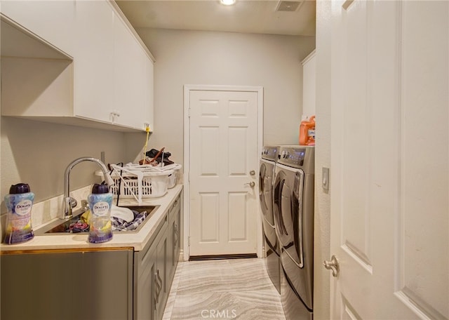 clothes washing area featuring separate washer and dryer, sink, light hardwood / wood-style flooring, and cabinets