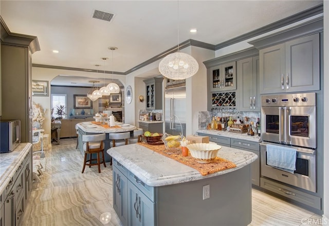 kitchen featuring appliances with stainless steel finishes, crown molding, a kitchen island, and pendant lighting