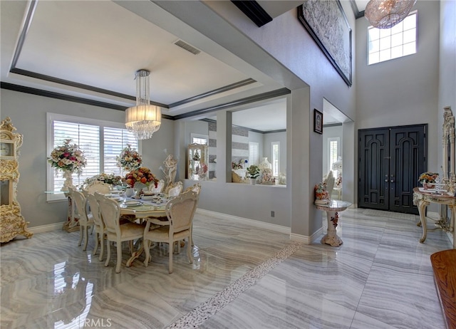 dining room with crown molding, a tray ceiling, and a notable chandelier