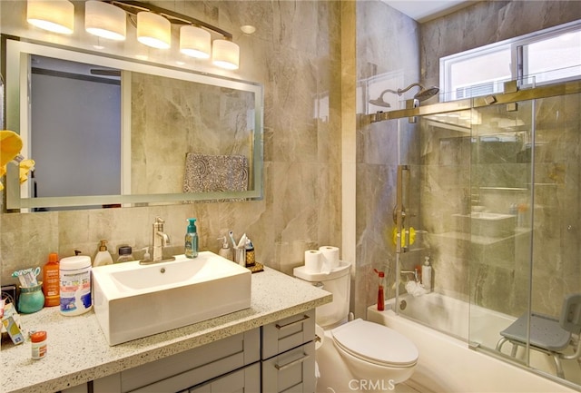 full bathroom featuring tile walls, decorative backsplash, vanity, shower / bath combination with glass door, and toilet