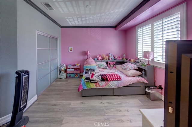 bedroom featuring light wood-type flooring, crown molding, and heating unit