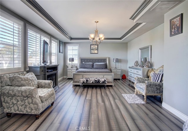 bedroom featuring a tray ceiling, dark hardwood / wood-style floors, and a chandelier