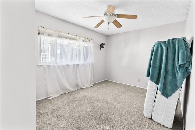 unfurnished room with ceiling fan, carpet floors, and a textured ceiling