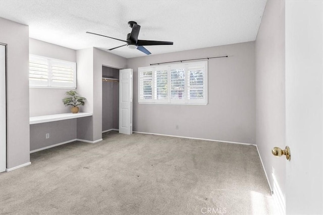 unfurnished bedroom with ceiling fan, light colored carpet, a textured ceiling, and a closet