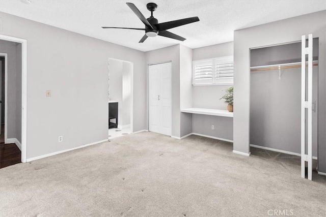 unfurnished bedroom featuring light colored carpet, ceiling fan, and multiple closets