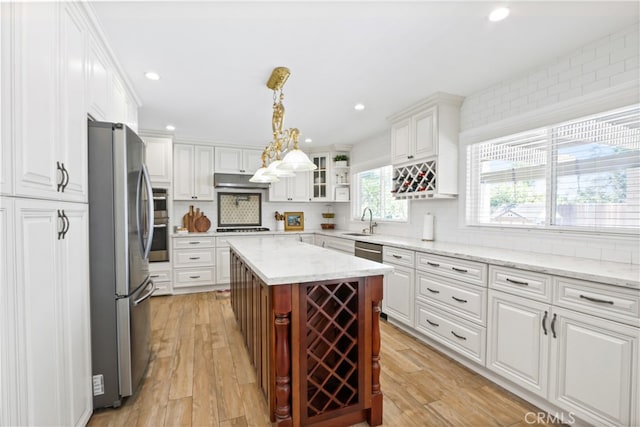 kitchen with appliances with stainless steel finishes, light hardwood / wood-style floors, white cabinetry, tasteful backsplash, and sink