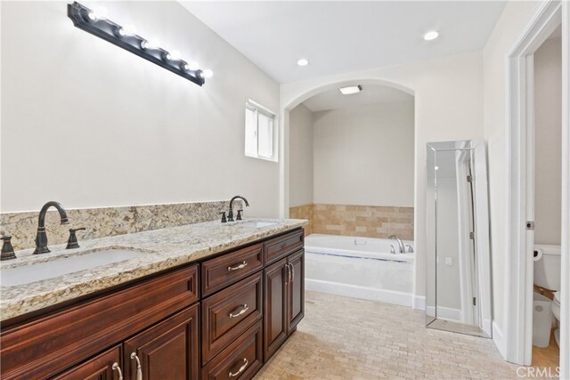 bathroom with vanity, a washtub, and toilet