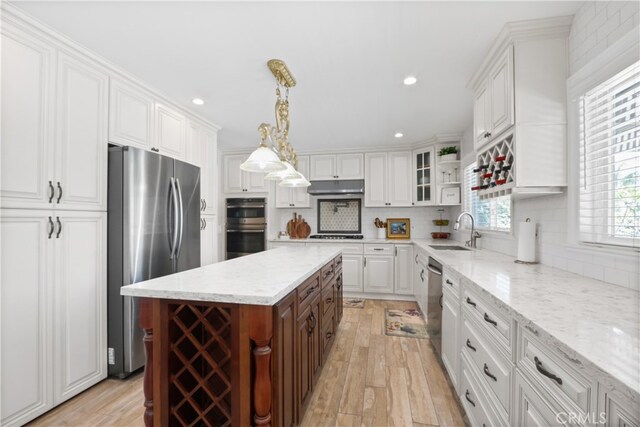 kitchen featuring stainless steel appliances, hanging light fixtures, light wood-type flooring, and sink