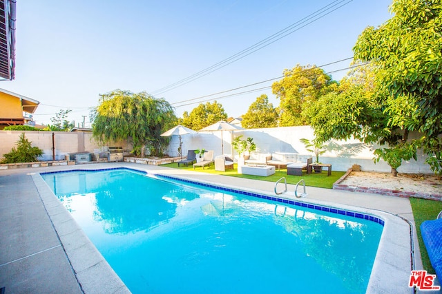 view of pool with an outdoor living space and a patio area