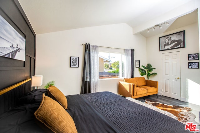 bedroom featuring track lighting, wood-type flooring, and vaulted ceiling