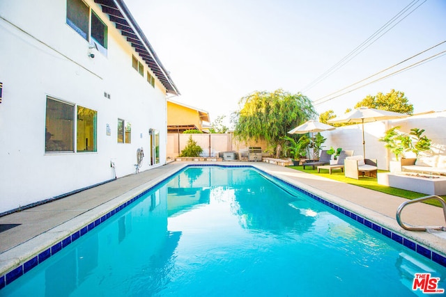 view of pool with grilling area and a patio