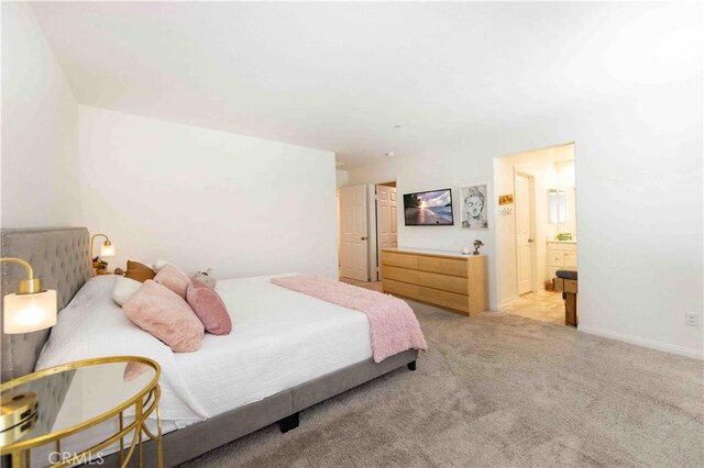 bedroom featuring light colored carpet and ensuite bath