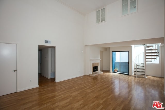 unfurnished living room featuring hardwood / wood-style flooring and a towering ceiling