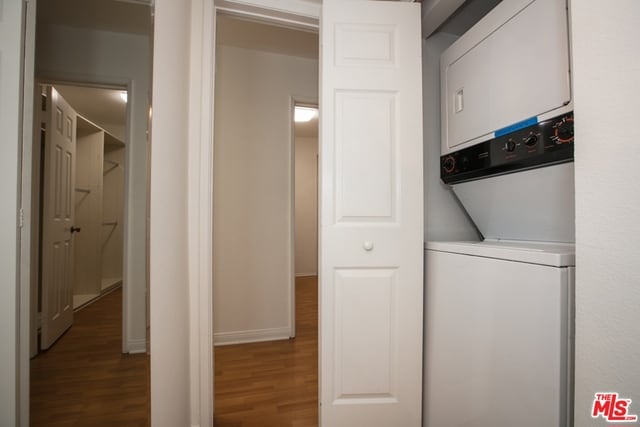 washroom featuring wood-type flooring and stacked washer and clothes dryer