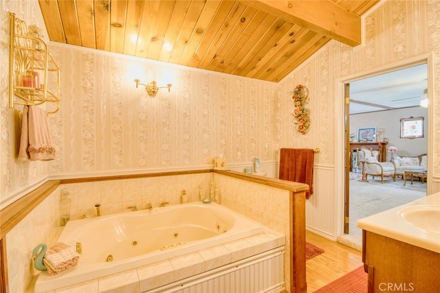 bathroom with lofted ceiling with beams, tiled bath, hardwood / wood-style flooring, vanity, and wooden ceiling