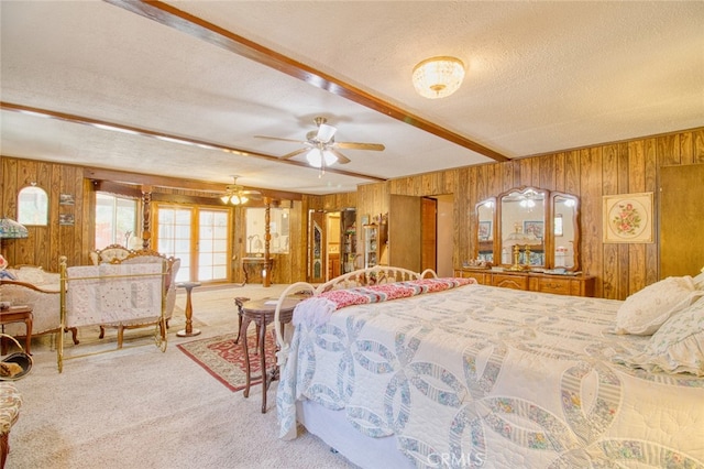 bedroom featuring beamed ceiling, wooden walls, carpet floors, and a textured ceiling