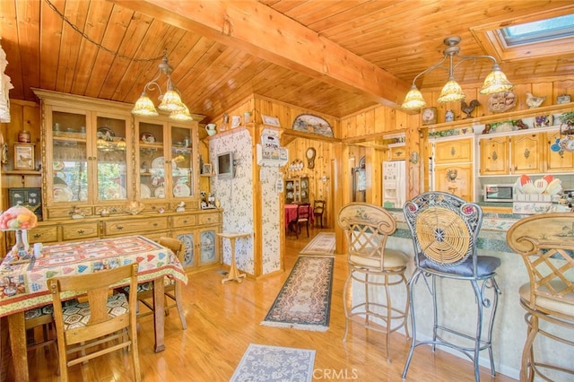 dining area with wood ceiling, vaulted ceiling with skylight, and light hardwood / wood-style flooring