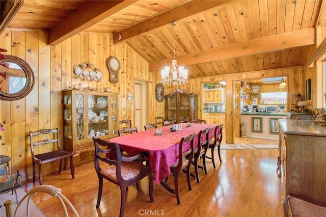 dining space with an inviting chandelier, wood ceiling, wooden walls, and light hardwood / wood-style floors