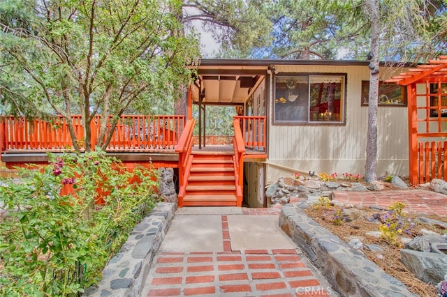 view of exterior entry with a deck and a patio