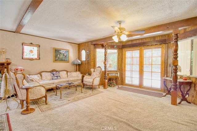 living room featuring beamed ceiling, ceiling fan, carpet, and a textured ceiling