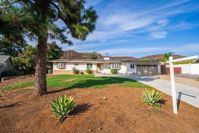 single story home with a mountain view, a front yard, and a garage