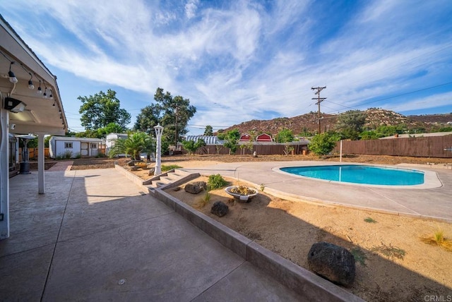 view of pool with an outbuilding, a mountain view, and a patio area