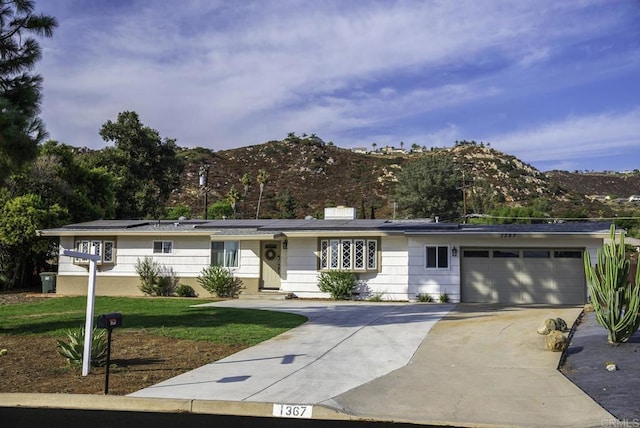 single story home featuring a mountain view, a garage, and a front lawn