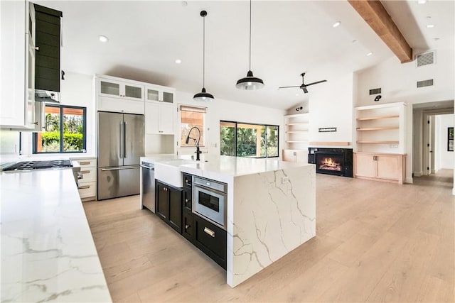 kitchen featuring appliances with stainless steel finishes, light hardwood / wood-style flooring, white cabinetry, and hanging light fixtures