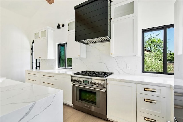 kitchen with white cabinets, custom range hood, high end stainless steel range oven, and light stone counters