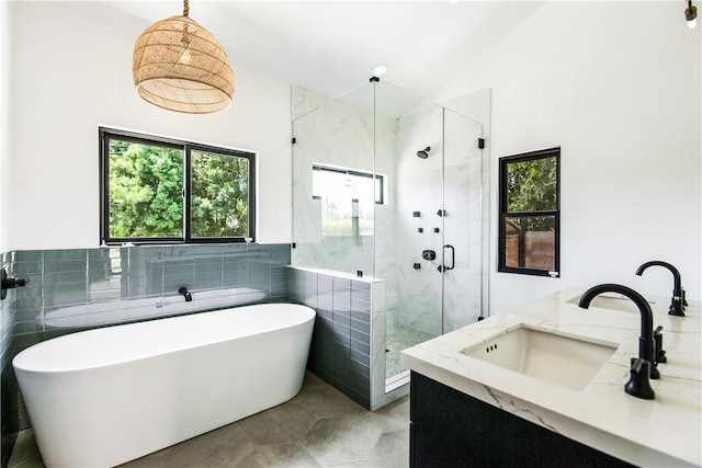 bathroom featuring plus walk in shower, vanity, tile patterned floors, and tile walls