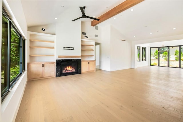 unfurnished living room featuring high vaulted ceiling, a high end fireplace, ceiling fan with notable chandelier, light hardwood / wood-style flooring, and beamed ceiling