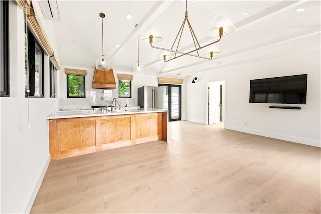 kitchen featuring kitchen peninsula, stainless steel fridge, decorative light fixtures, and light hardwood / wood-style flooring