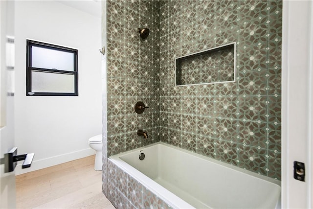 bathroom with tiled shower / bath combo and toilet