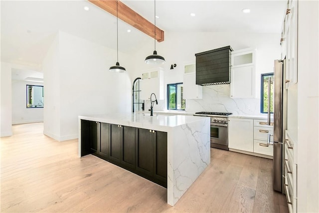 kitchen featuring white cabinets, lofted ceiling with beams, a spacious island, sink, and appliances with stainless steel finishes