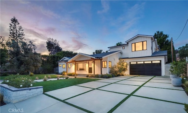 modern inspired farmhouse featuring a yard, covered porch, board and batten siding, a garage, and driveway