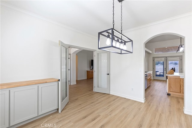 dining room with french doors, ornamental molding, a notable chandelier, and light hardwood / wood-style floors