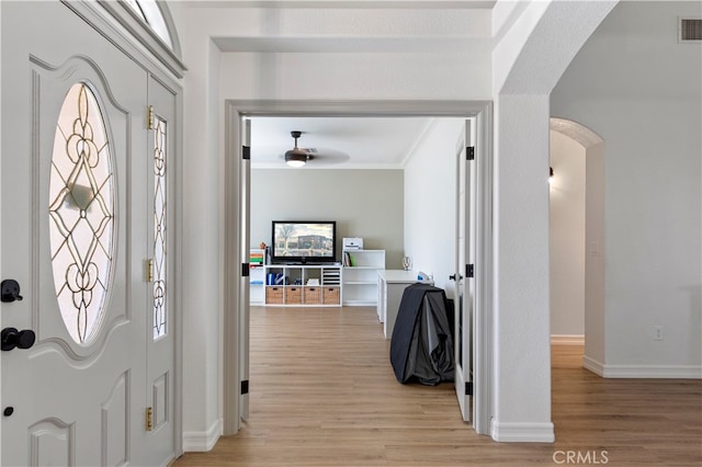 foyer entrance featuring light hardwood / wood-style floors, ornamental molding, and ceiling fan