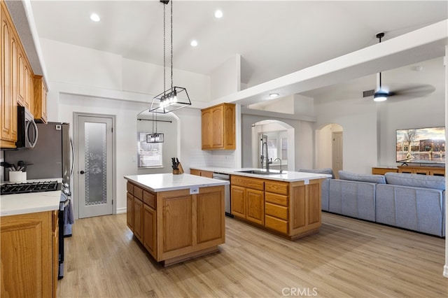 kitchen with hanging light fixtures, kitchen peninsula, a kitchen island, appliances with stainless steel finishes, and light hardwood / wood-style floors