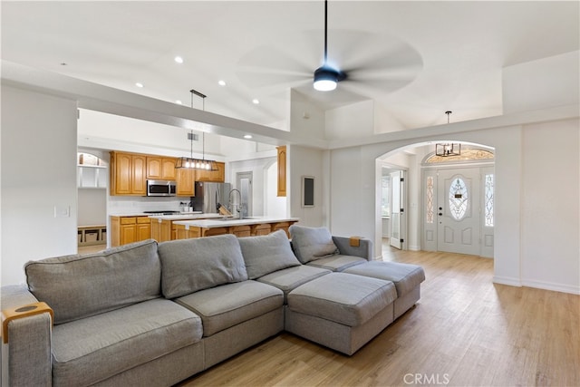 living room featuring light wood-type flooring, sink, ceiling fan, and high vaulted ceiling