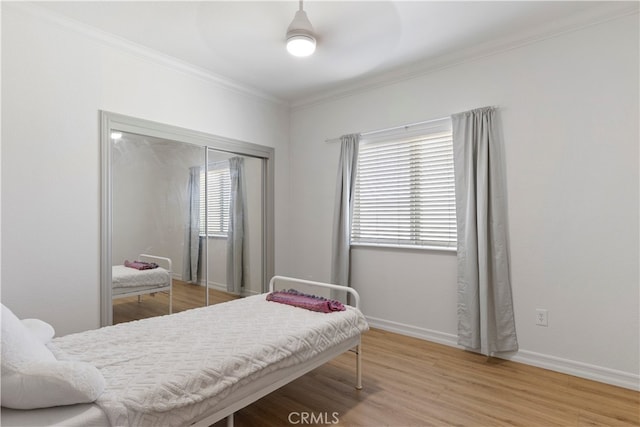 bedroom with multiple windows, wood-type flooring, ceiling fan, and a closet