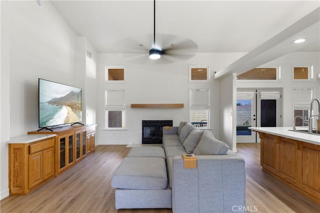 living room featuring ceiling fan, sink, and light hardwood / wood-style floors