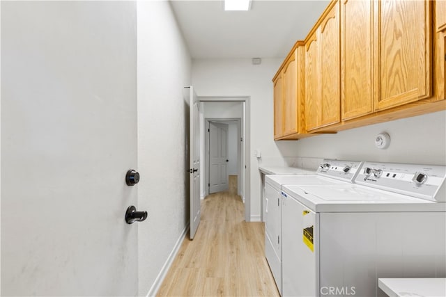 laundry area with separate washer and dryer, cabinets, and light hardwood / wood-style flooring