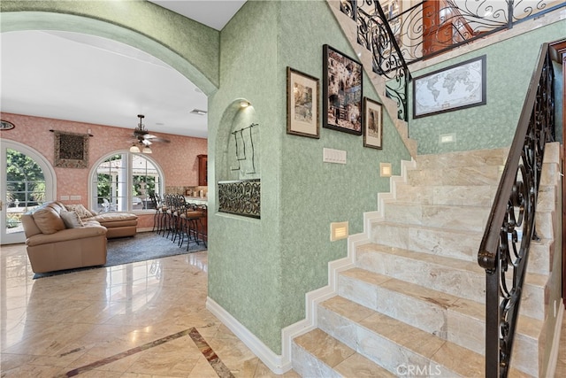 stairway featuring ceiling fan