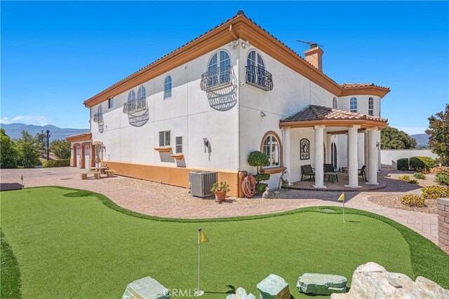 rear view of property featuring central air condition unit, a mountain view, and a patio area