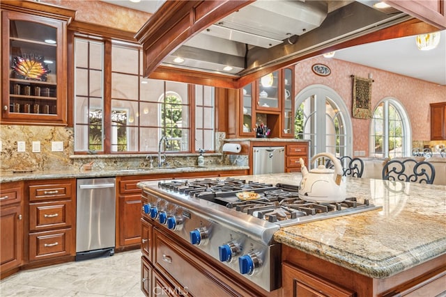 kitchen with stainless steel gas cooktop, tasteful backsplash, light stone countertops, and sink